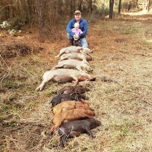 Man and child standing with euthanized boar from the Pig Brig trap system